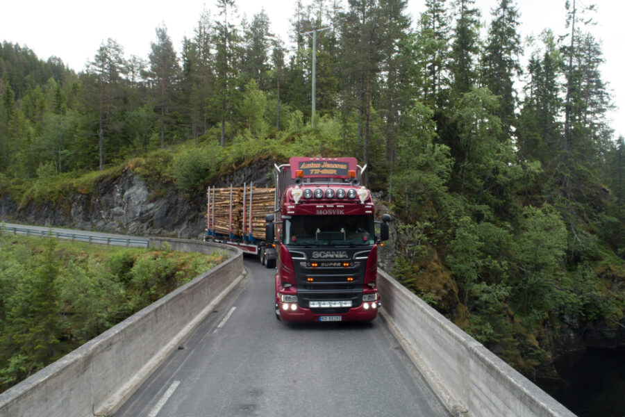 Tømmerbil med lass på vei over bru.