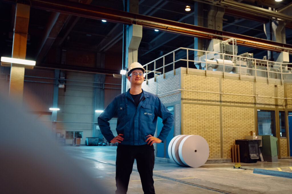 Mann med hjelm i papirfabrikk.