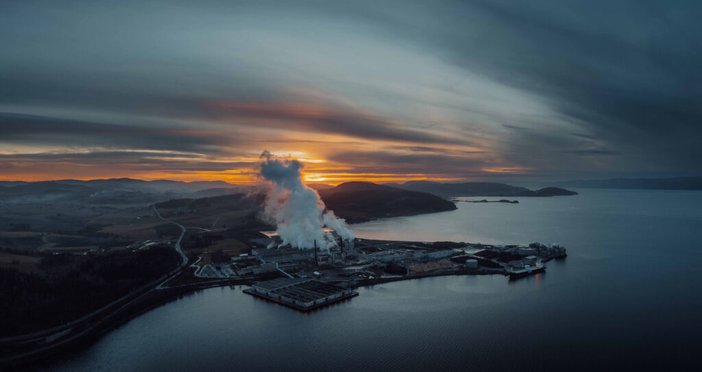 Papirfabrikk ved fjorden om kvelden. Bilde tatt fra lufta.