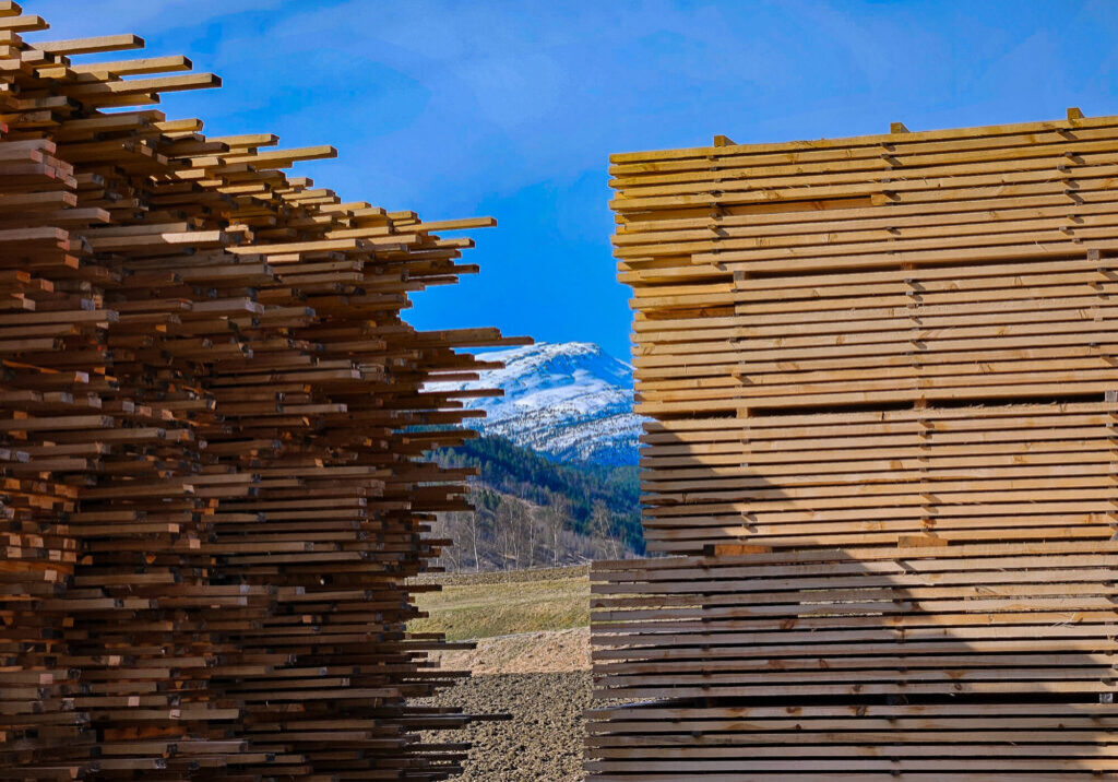 To stabler tremateriale med fjell bak.