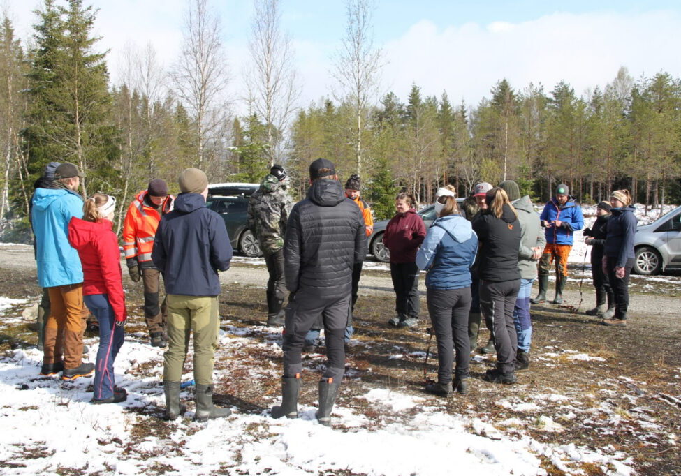 Gruppe mennesker samlet rundt bål i skogen.